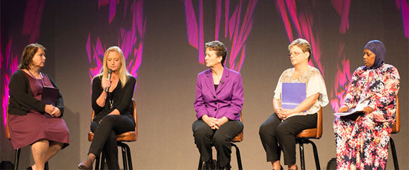 5 women sitting on stage participating in a panel discussion